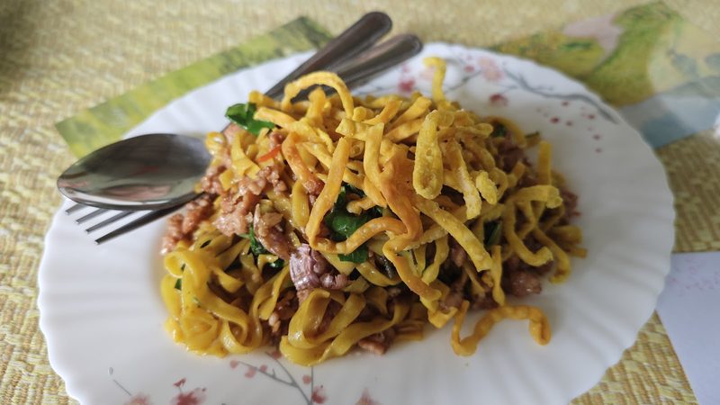 ข้าวซอยผัดเส้นเหลืองกับหมูสับบนจานกระเบื้อง