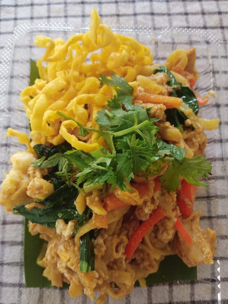 ข้าวซอยกรอบสีเหลืองทองโรยผักและสมุนไพร